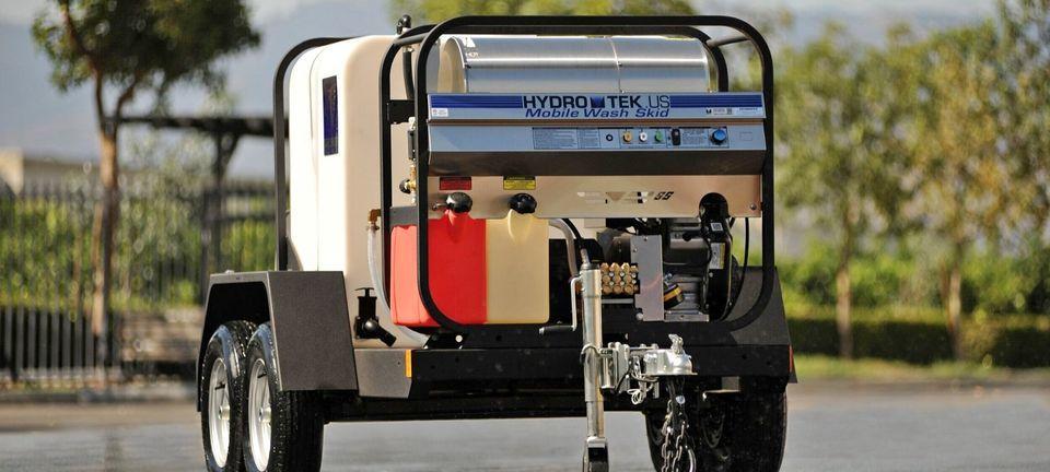 Hydro Tek mobile wash skid mounted on a trailer, parked outdoors with trees in the background.